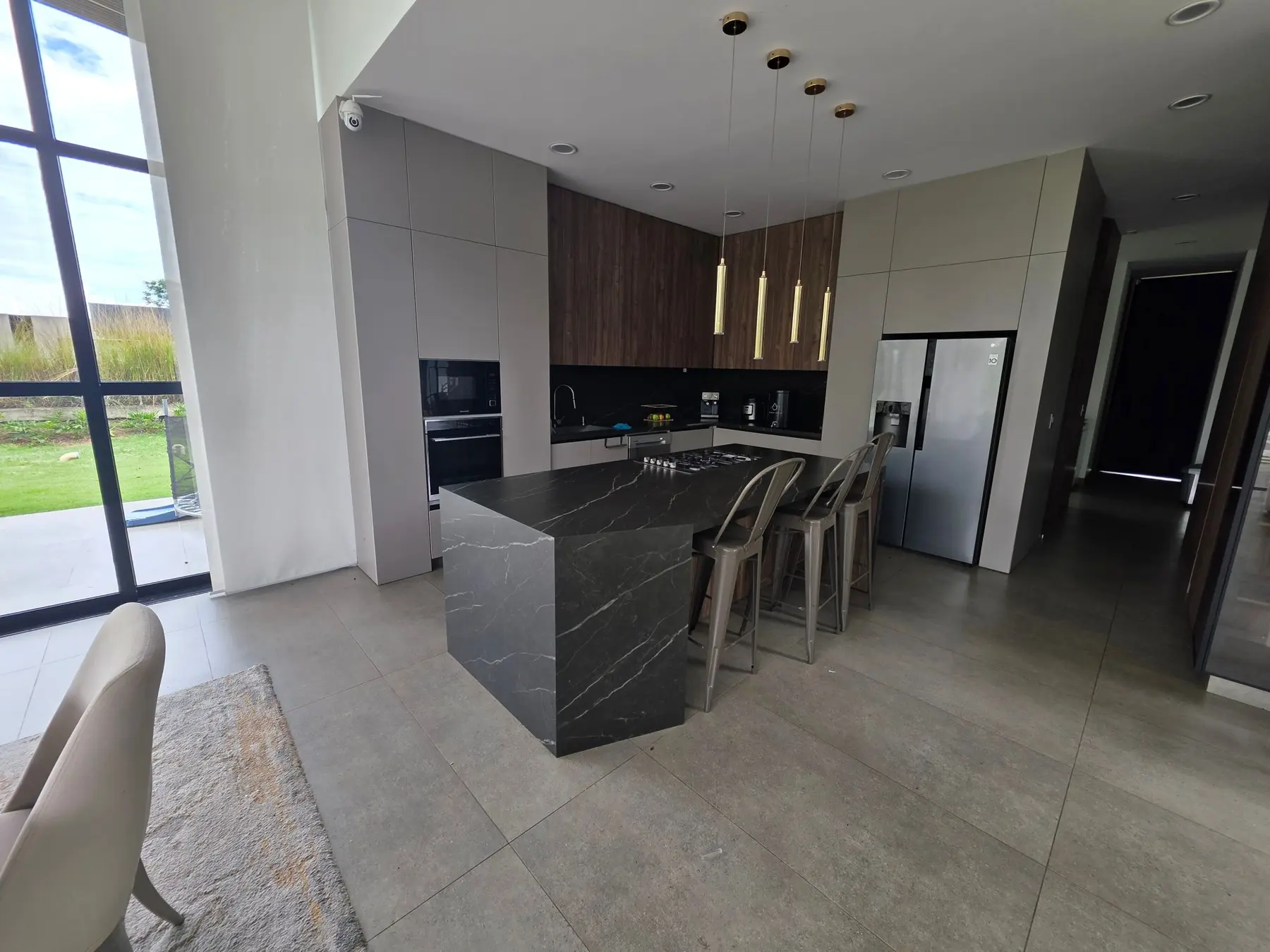 Isla de cocina en piedra oscura veteada con taburetes